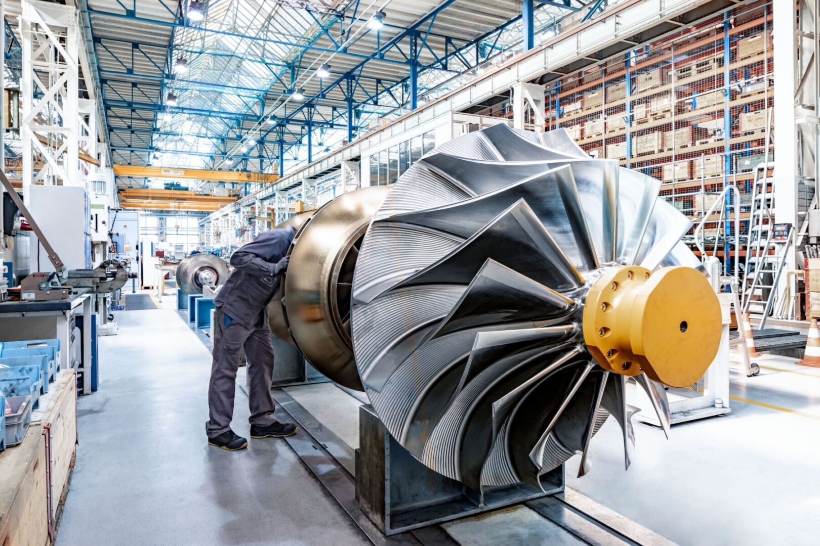 INZH27 Everllence sme Scanderbeg Sauer 01 A technician works on a large, metallic industrial turbine inside a bright factory.