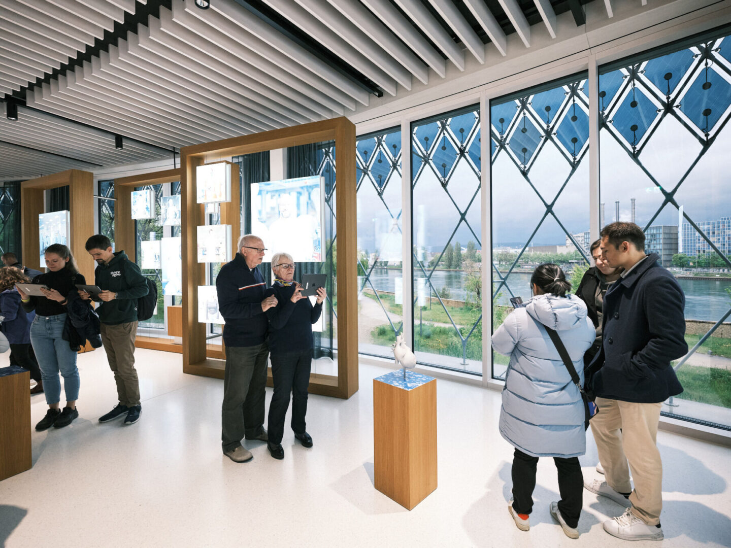 IN24 015 Web Res Samuel Bramley Menschen betrachten Exponate und digitale Bildschirme in einem modernen, hellen Ausstellungsraum.