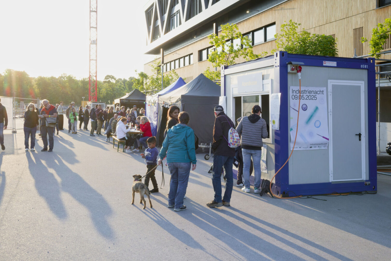 Industrienacht Regio Basel 2026 uptown Foto Flavia Schaub Menschen versammeln sich bei einer Veranstaltung vor einem blauen Container und Zelten.
